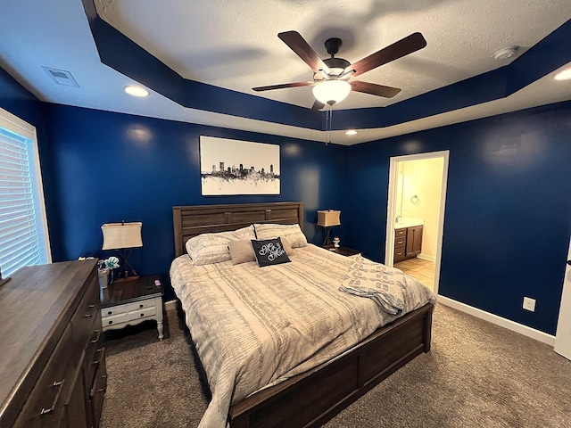 bedroom featuring carpet, a tray ceiling, visible vents, baseboards, and a textured ceiling