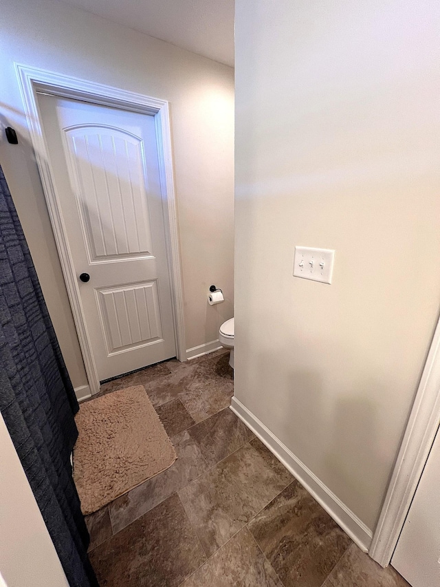 bathroom with toilet and baseboards