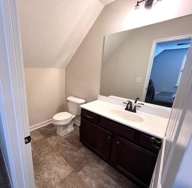 bathroom featuring lofted ceiling, a textured ceiling, toilet, and vanity