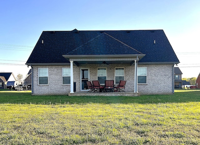 back of house featuring a patio area, a shingled roof, brick siding, and a yard
