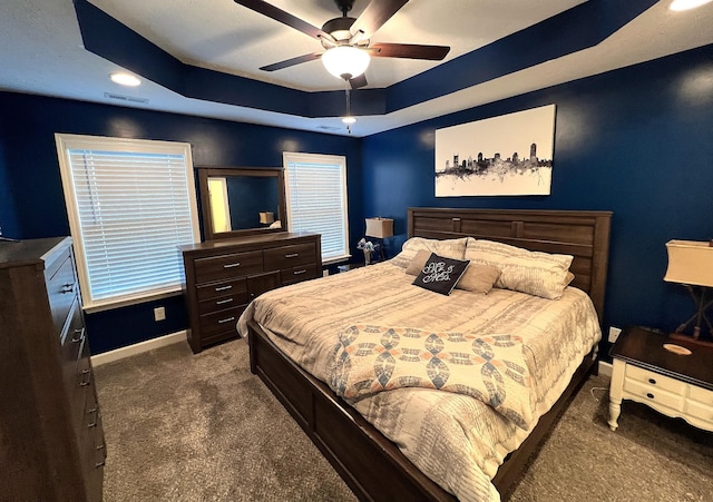 bedroom with a ceiling fan, a raised ceiling, baseboards, carpet flooring, and visible vents