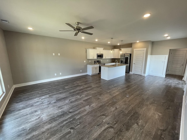 kitchen featuring stainless steel appliances, a center island with sink, open floor plan, baseboards, and ceiling fan