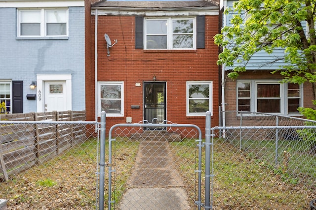 view of property with a gate, brick siding, and a fenced front yard