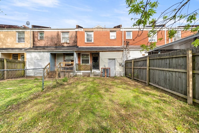 back of house with central air condition unit, a lawn, and a fenced backyard