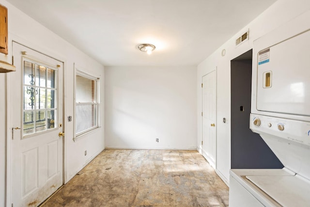 washroom with stacked washer and clothes dryer, visible vents, and baseboards