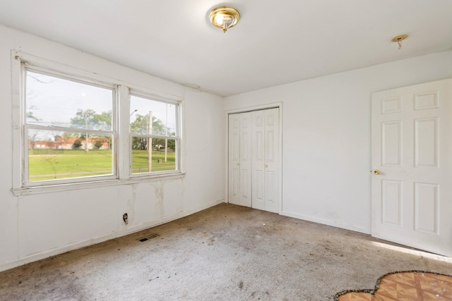 unfurnished bedroom with baseboards, carpet flooring, visible vents, and a closet
