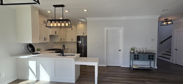 kitchen featuring black refrigerator with ice dispenser, crown molding, a sink, light countertops, and dark wood-type flooring
