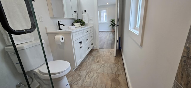 bathroom featuring marble finish floor, baseboards, toilet, and vanity
