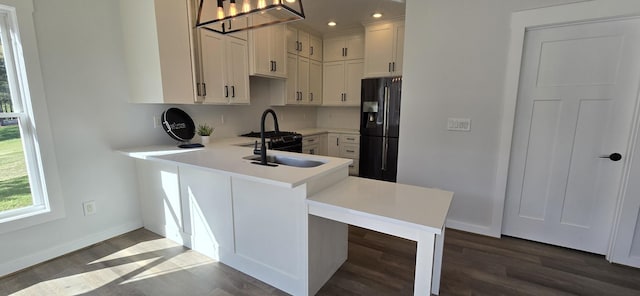 kitchen featuring black refrigerator with ice dispenser, wood finished floors, light countertops, baseboards, and a notable chandelier
