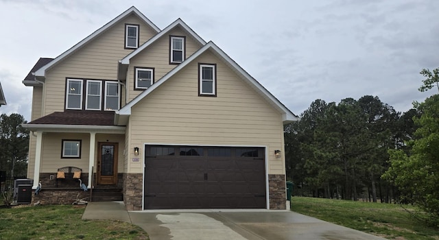 craftsman inspired home with central AC unit, concrete driveway, stone siding, covered porch, and a garage