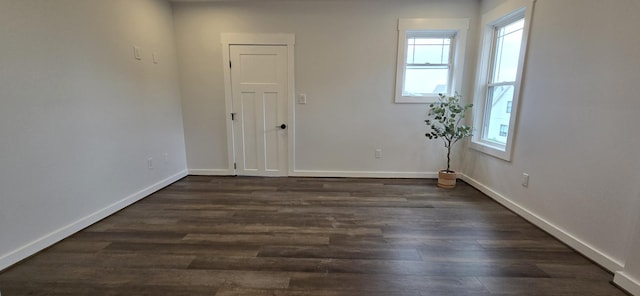 spare room with baseboards and dark wood-style flooring