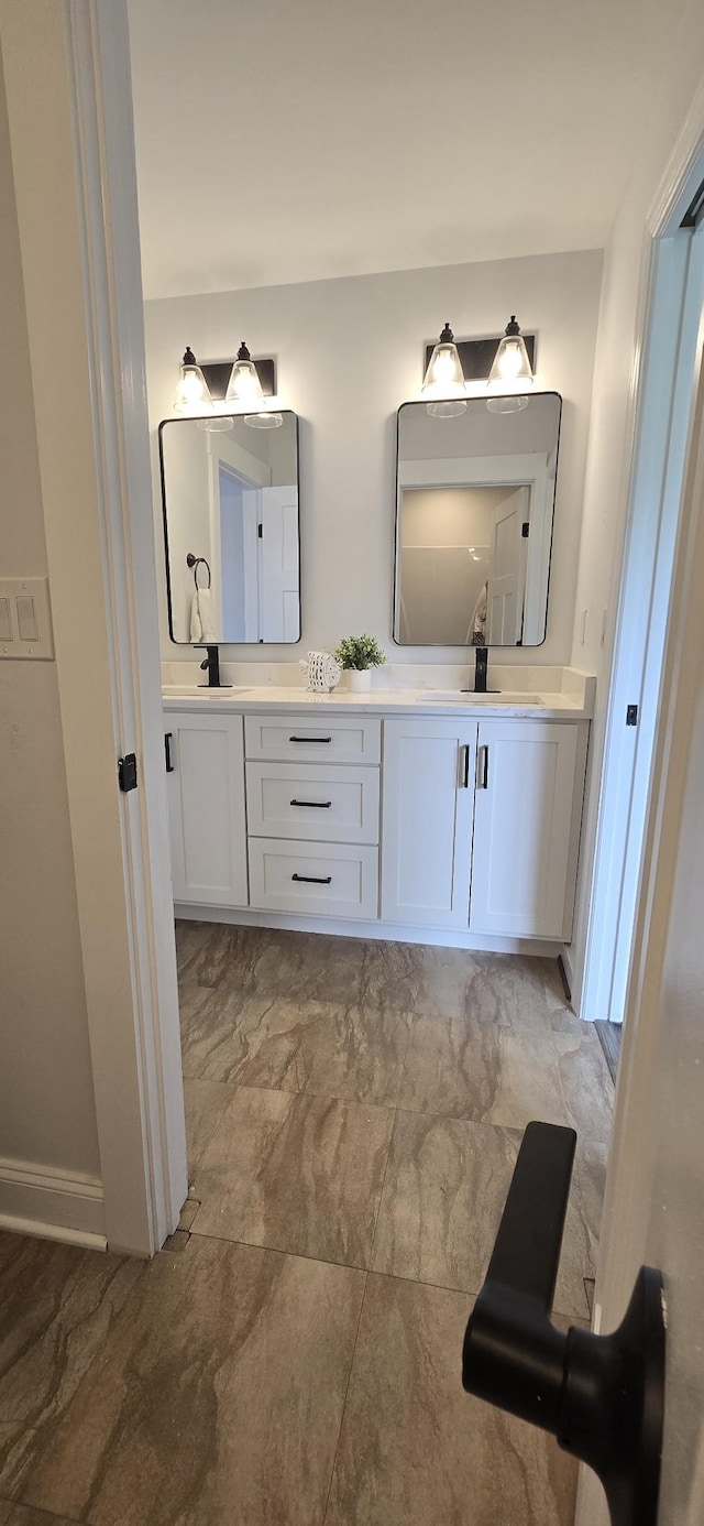 full bath with baseboards, a sink, and double vanity