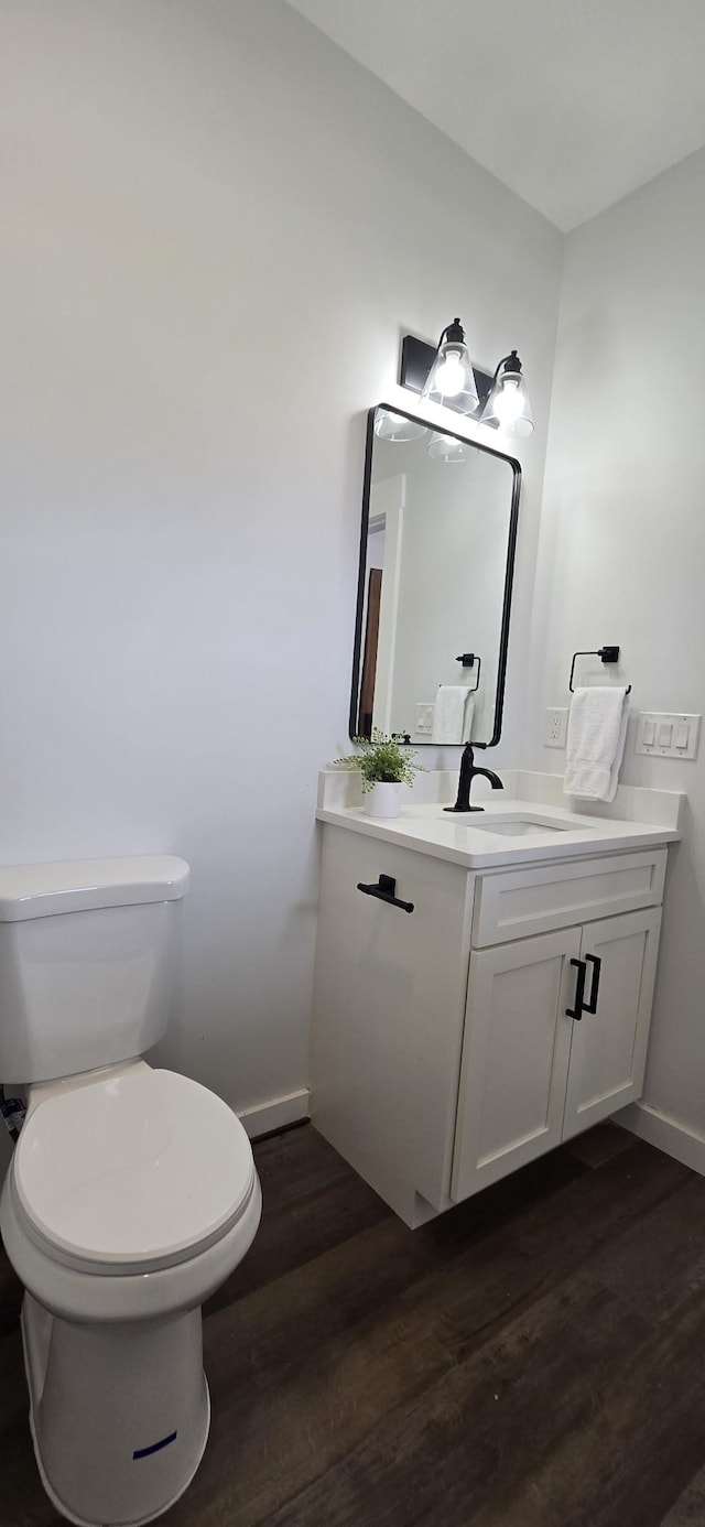 bathroom with wood finished floors, baseboards, vanity, and toilet