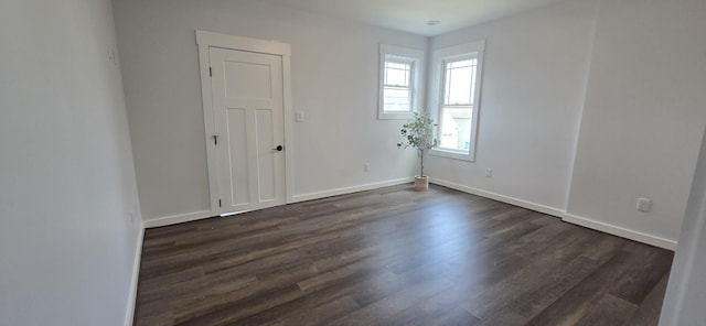 spare room with dark wood-type flooring and baseboards