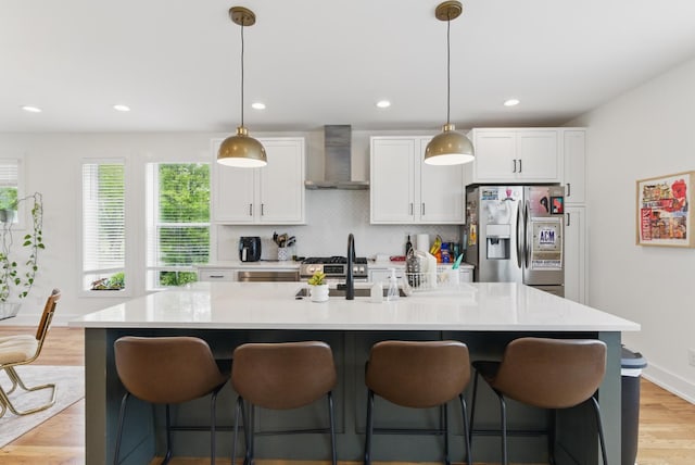 2006 Manchester Ave, Nashville, TN 37218 - kitchen featuring white cabinetry, a kitchen bar, wall chimney range hood, an island with sink, and appliances with stainless steel finishes