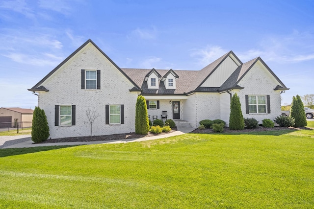 view of front of property featuring brick siding, roof with shingles, a front yard, and fence