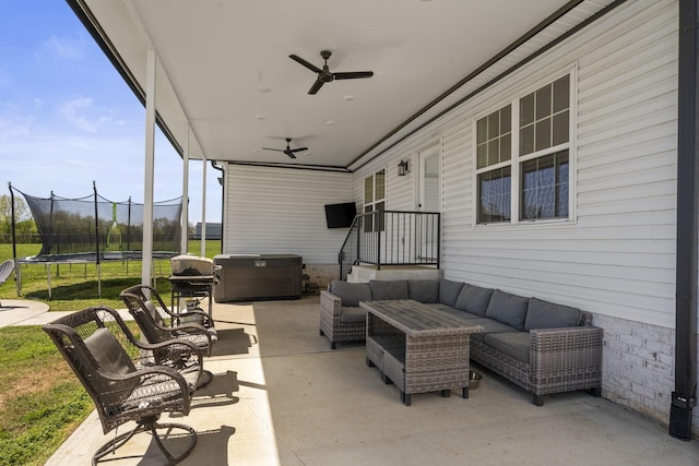 view of patio with a ceiling fan, outdoor lounge area, fence, a hot tub, and a trampoline