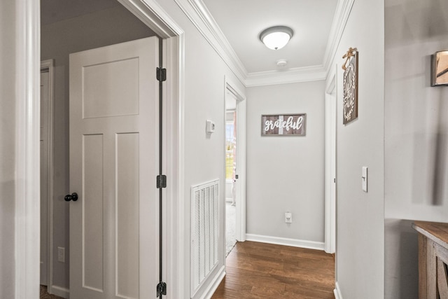 corridor with dark wood finished floors, visible vents, baseboards, and ornamental molding