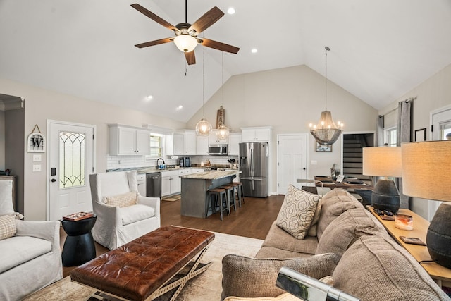living area with ceiling fan with notable chandelier, high vaulted ceiling, recessed lighting, and dark wood-style flooring