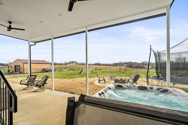 sunroom / solarium featuring a hot tub, a ceiling fan, and an outdoor fire pit