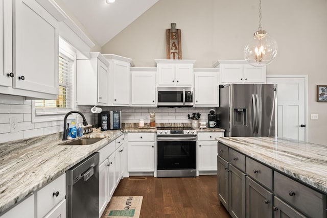 kitchen featuring stainless steel appliances, a sink, vaulted ceiling, backsplash, and white cabinetry