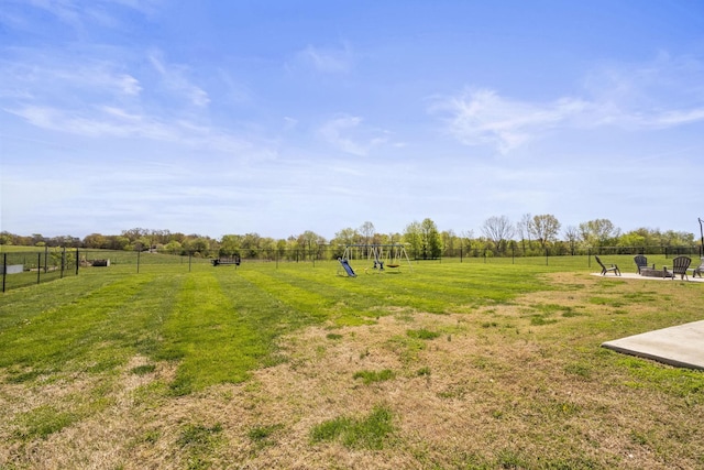 view of yard with fence, playground community, a patio area, a rural view, and an outdoor fire pit