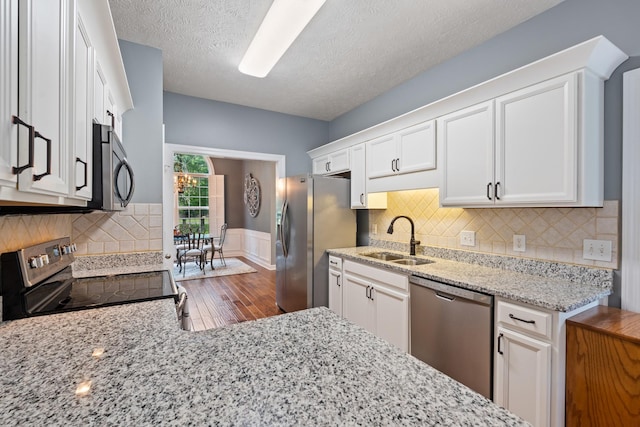 102 Munson Ct, Smyrna, TN 37167 - kitchen with appliances with stainless steel finishes, a sink, white cabinets, light stone countertops, and wood finished floors