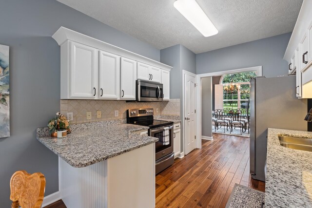 102 Munson Ct, Smyrna, TN 37167 - kitchen featuring stainless steel appliances, dark wood-style floors, white cabinets, backsplash, and a peninsula