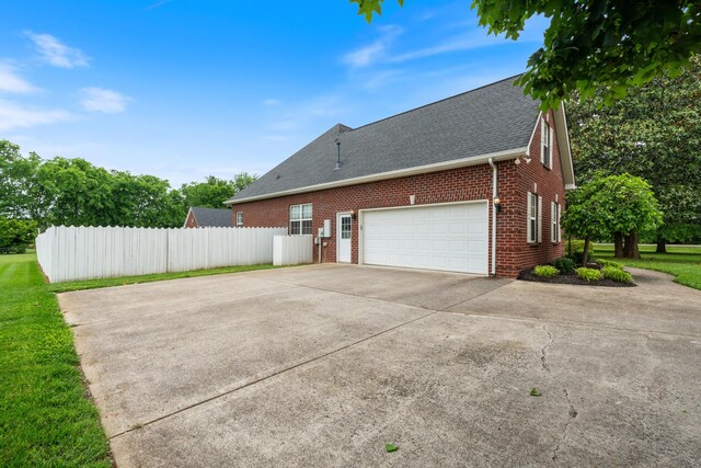 102 Munson Ct, Smyrna, TN 37167 - view of side of home featuring brick siding, fence, driveway, an attached garage, and a shingled roof