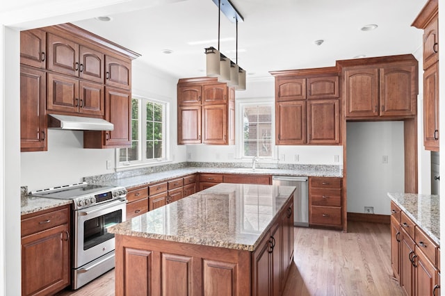 1008 Green Hill Cv, Brentwood, TN 37027 - kitchen with under cabinet range hood, stainless steel appliances, brown cabinetry, light stone countertops, and light wood-style flooring