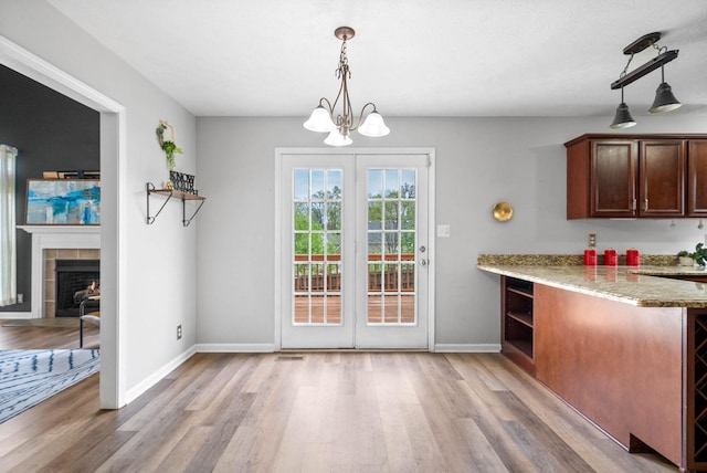 3051 Outfitters Dr, Clarksville, TN 37040 - unfurnished dining area with light wood-style floors, a tiled fireplace, visible vents, and baseboards
