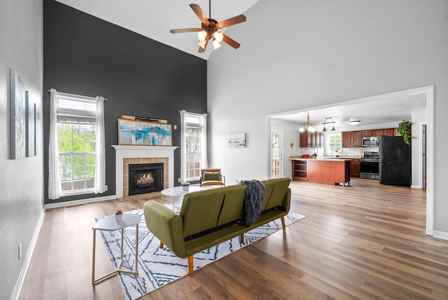 3051 Outfitters Dr, Clarksville, TN 37040 - living area with a healthy amount of sunlight, a tiled fireplace, light wood-style floors, a ceiling fan, and high vaulted ceiling