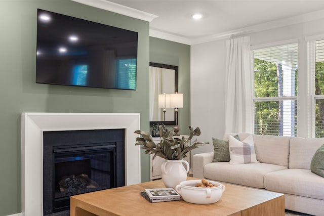 living room with recessed lighting, a glass covered fireplace, and crown molding