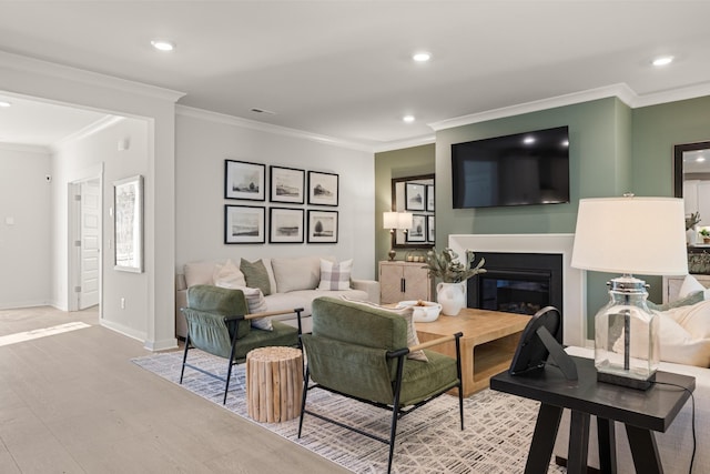 living area featuring recessed lighting, wood finished floors, crown molding, baseboards, and a glass covered fireplace