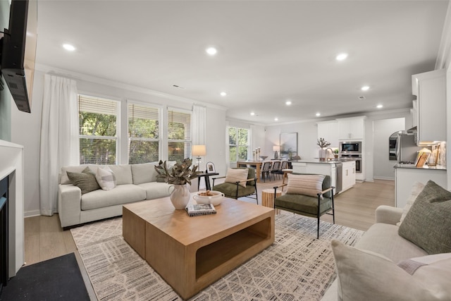 living area featuring a fireplace, ornamental molding, light wood finished floors, and recessed lighting