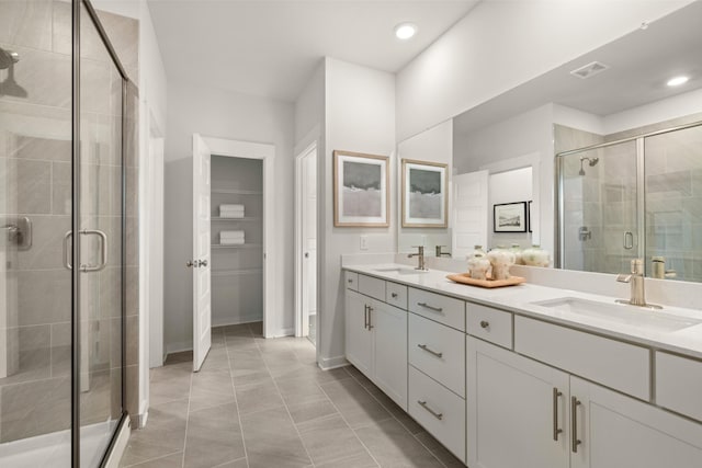 bathroom featuring double vanity, visible vents, a stall shower, and a sink