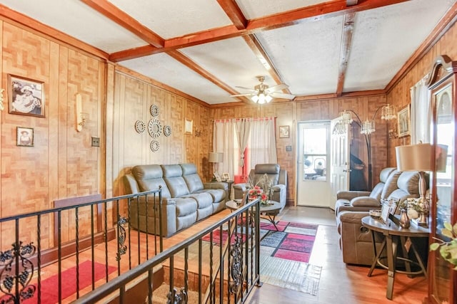 living room with wood finished floors, beam ceiling, a ceiling fan, and wood walls