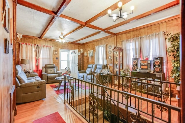 interior space with wood finished floors, ceiling fan with notable chandelier, wooden walls, coffered ceiling, and beam ceiling