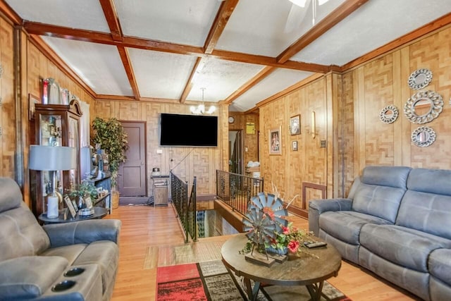 living area featuring beam ceiling, an inviting chandelier, coffered ceiling, wood walls, and wood finished floors