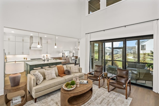 living area with light wood finished floors, a high ceiling, and recessed lighting