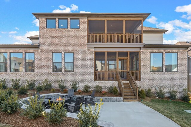 rear view of house featuring a fire pit, brick siding, a patio, and a sunroom