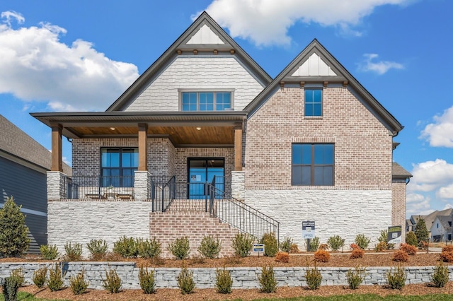view of front facade with stone siding, a porch, brick siding, and board and batten siding