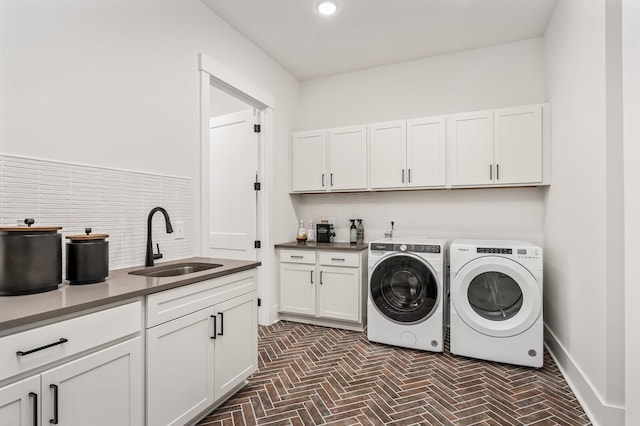 laundry area featuring cabinet space, independent washer and dryer, brick floor, and a sink