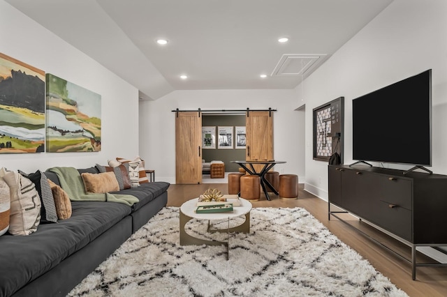living room featuring a barn door, vaulted ceiling, wood finished floors, and recessed lighting
