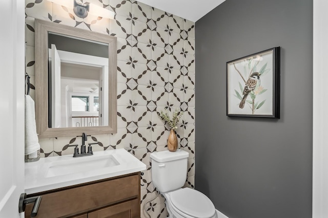 bathroom with tile walls, toilet, and vanity