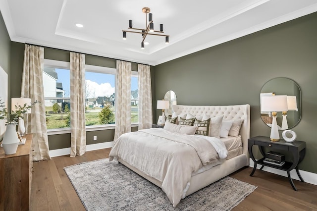 bedroom with baseboards, an inviting chandelier, recessed lighting, wood finished floors, and a raised ceiling