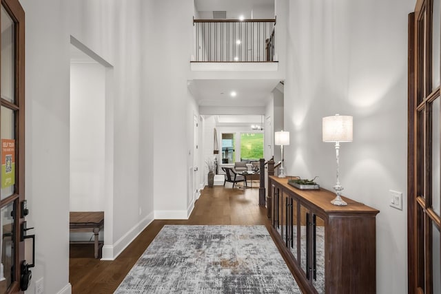 entryway with baseboards, a towering ceiling, and dark wood-style floors