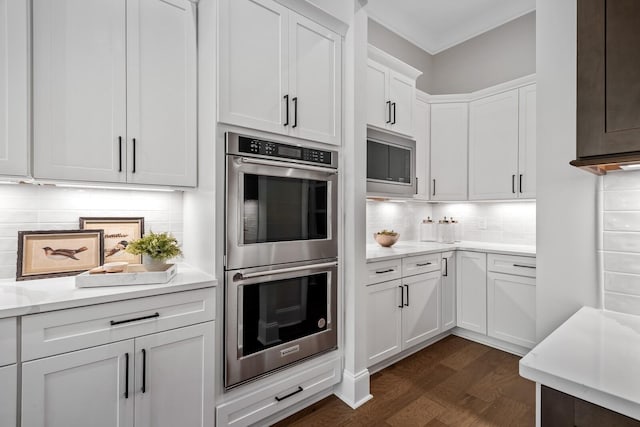 kitchen with ornamental molding, white cabinetry, appliances with stainless steel finishes, and tasteful backsplash