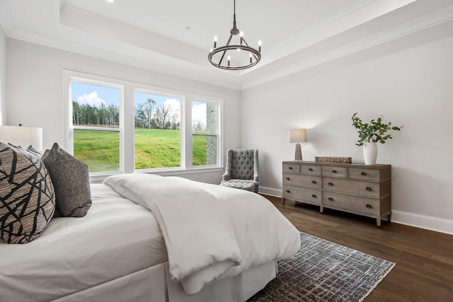 bedroom with a tray ceiling, dark wood-style flooring, baseboards, a notable chandelier, and ornamental molding