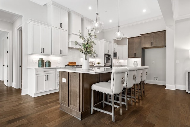 kitchen featuring dark wood finished floors, backsplash, a kitchen island with sink, and light countertops